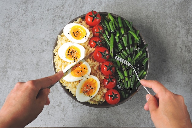 Ciotola di Buddha con bulgur, fagiolini, pomodorini e metà dell'uovo sodo. Cibo sano in una ciotola. Il concetto di nutrizione dietetica.