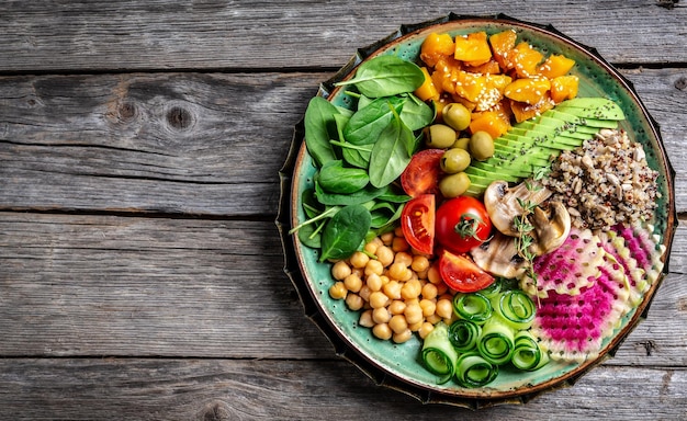 Ciotola di Buddha con Quinoa Avocado funghi cetrioli ceci spinaci pomodori verdure insalata Pulire mangiare dieta cibo vegano concetto vista dall'alto