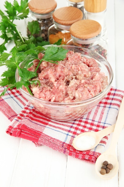 Ciotola di carne macinata cruda con spezie sulla tavola di legno