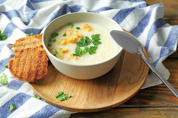 Ciotola di ceramica con zuppa di crema di patate su tavola di legno