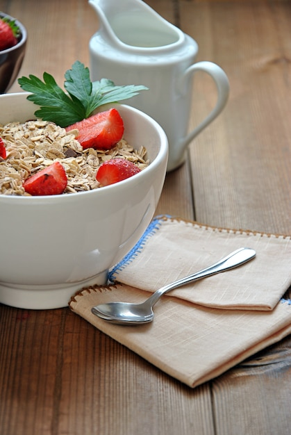 Ciotola di cereali con latte e fragole sul tavolo di legno