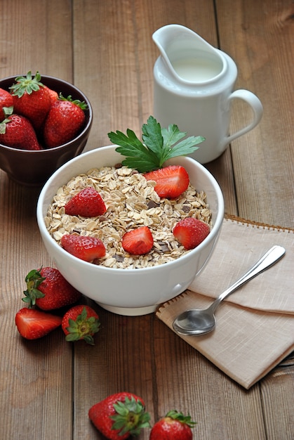 Ciotola di cereali con latte e fragole sul tavolo di legno