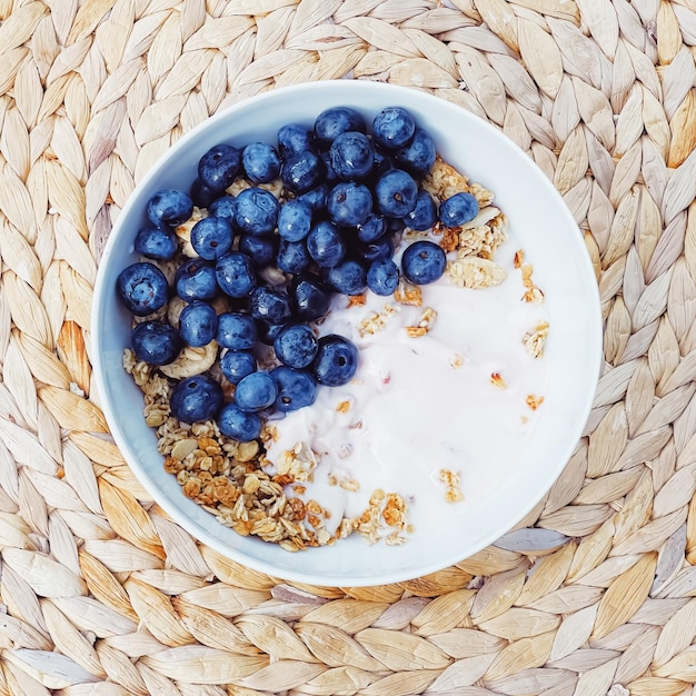 Ciotola di cereali con yogurt al mirtillo come colazione sana e cibo dolce per il pasto mattutino e dieta e nutrizione di frutti di bosco biologici