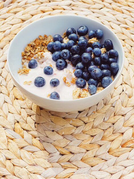 Ciotola di cereali con yogurt al mirtillo come colazione sana e cibo dolce per il pasto mattutino e dieta e nutrizione di frutti di bosco biologici