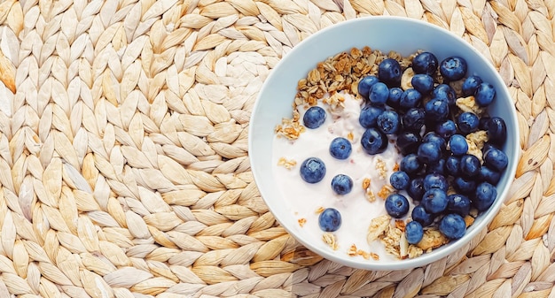 Ciotola di cereali con yogurt al mirtillo come colazione sana e cibo dolce per il pasto mattutino e dieta e nutrizione di frutti di bosco biologici