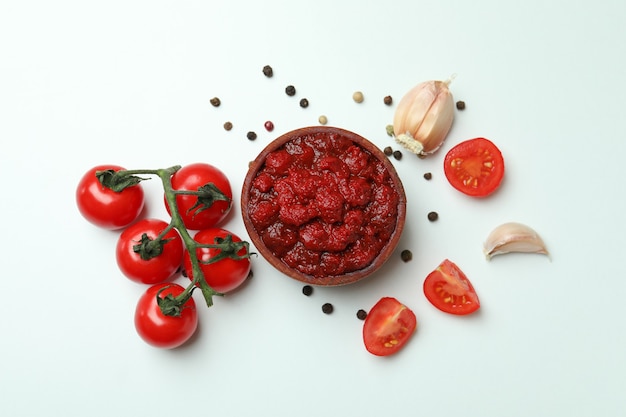 Ciotola di concentrato di pomodoro, pomodori, pepe e aglio su sfondo bianco