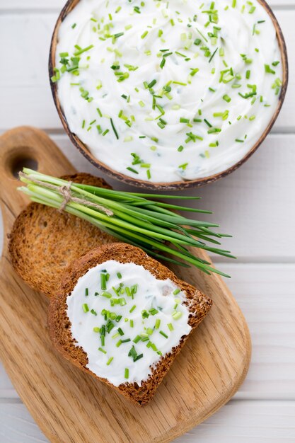 Ciotola di crema di formaggio con cipolle verdi, salsa di immersione sul tavolo di legno.