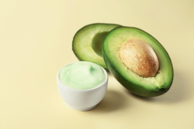 Ciotola di crema per il corpo con avocado su sfondo colorato