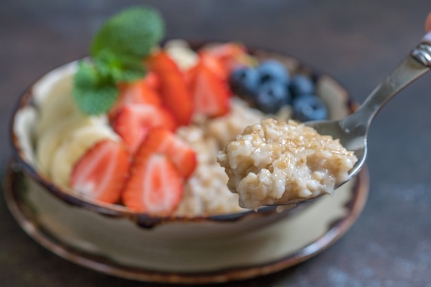 Ciotola di deliziosi avena tagliata in acciaio con frutta fresca, miele