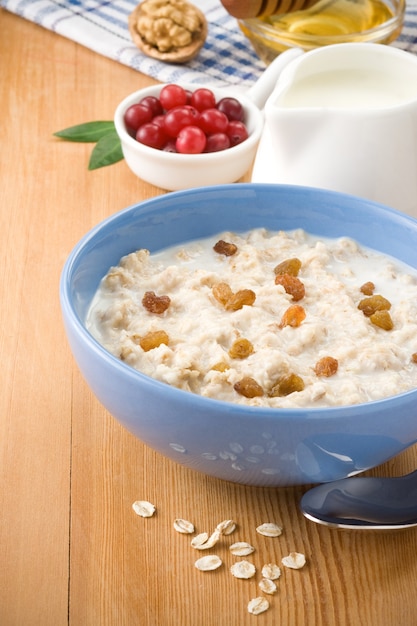 Ciotola di farina d'avena con frutti di bosco e latte su legno