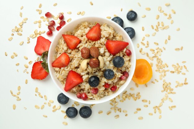 Ciotola di farina d'avena e ingredienti su sfondo bianco