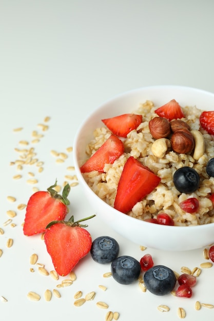 Ciotola di farina d'avena e ingredienti su sfondo bianco