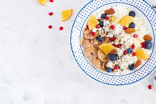 Ciotola di fiocchi con ricotta e yogurt, mirtilli e melograno sul tavolo bianco