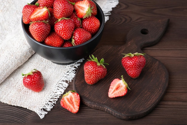 Ciotola di fragole rosse fresche sul tavolo di legno nero