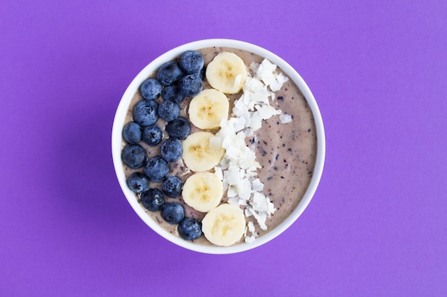 Ciotola di frullati con mirtilli, banana e cocco su viola