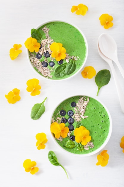 Ciotola di frullato di spinaci verdi con mirtillo, semi di chia e fiori di pansé commestibili