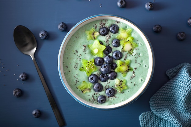 Ciotola di frullato di spirulina sana con mirtilli, stelle di kiwi, semi di chia