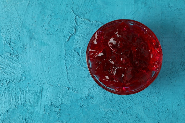 Ciotola di gelatina di fragole sul tavolo blu