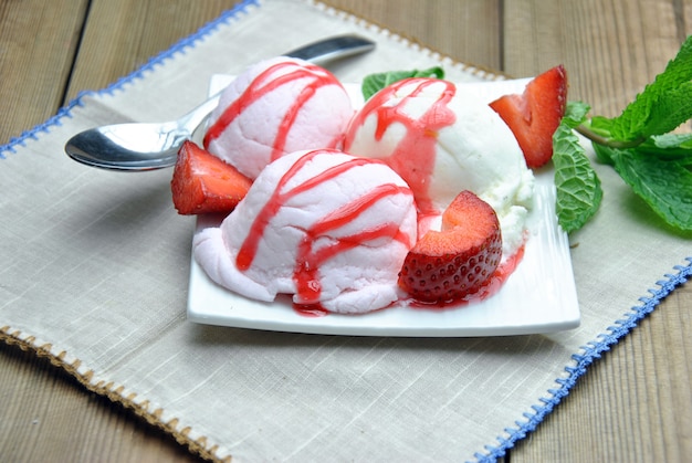 Ciotola di gelato con sciroppo di vaniglia e fragola, accompagnato da fragole