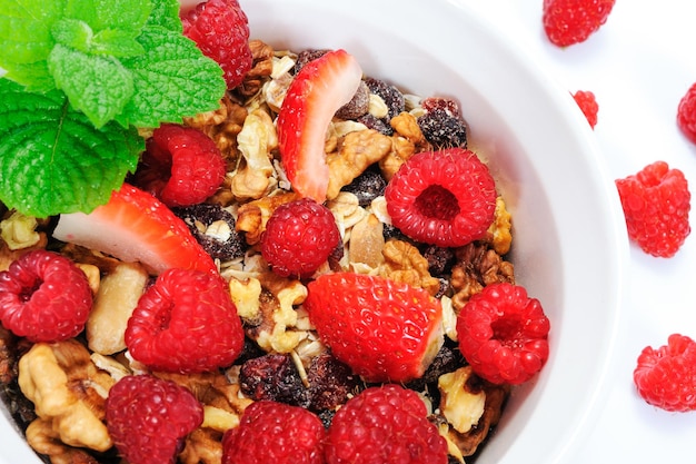 Ciotola di granola biologica fatta in casa con avena noci lamponi e fragole decorate con menta