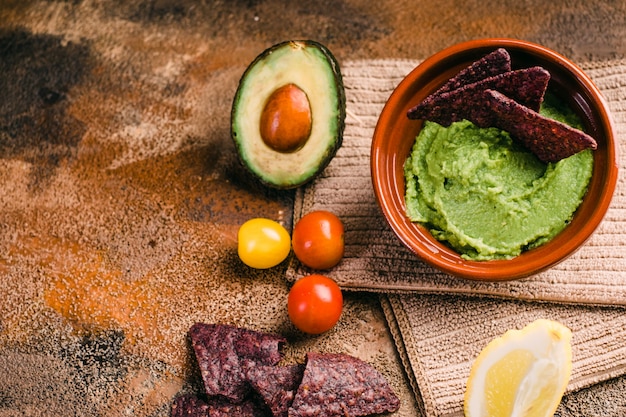 Ciotola di guacamole con gli ingredienti nel fondo di legno