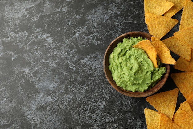 Ciotola di guacamole e patatine su sfondo nero smokey, spazio per il testo