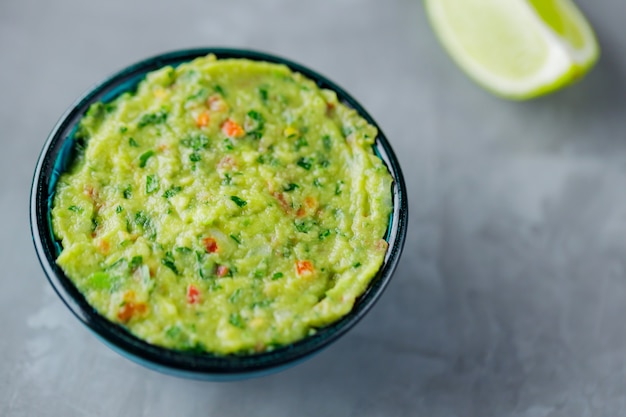 Ciotola di guacamole su uno sfondo grigio. Guacamole messicano tradizionale della salsa della immersione nella ciotola Cucina messicana. Copia spazio. Vista dall'alto