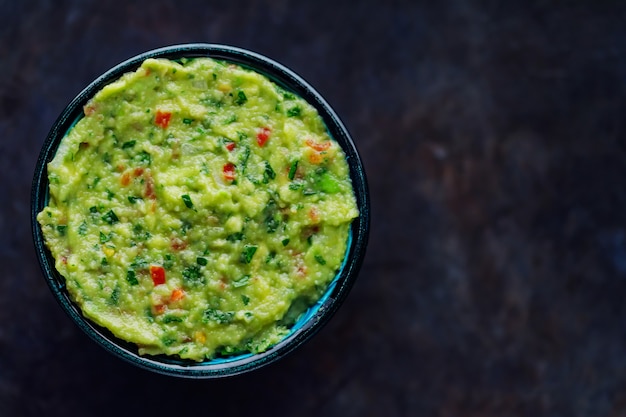 Ciotola di guacamole su uno sfondo scuro. Guacamole messicano tradizionale della salsa di tuffo Cibo messicano tradizionale. Copia spazio. Vista dall'alto