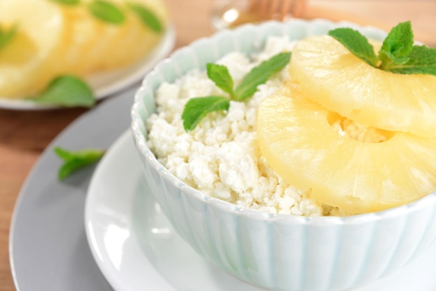 Ciotola di gustosa ricotta con ananas sulla tavola di legno