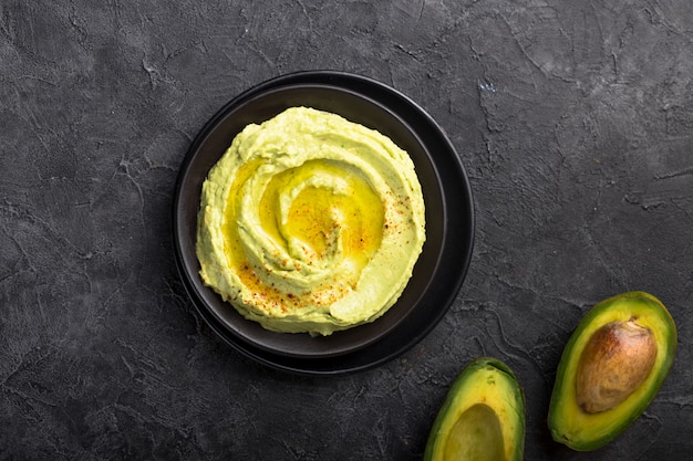 Ciotola di hummus verde, deliziosa crema di ceci e avocado su una superficie di pietra.