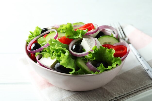 Ciotola di insalata greca su fondo di legno bianco