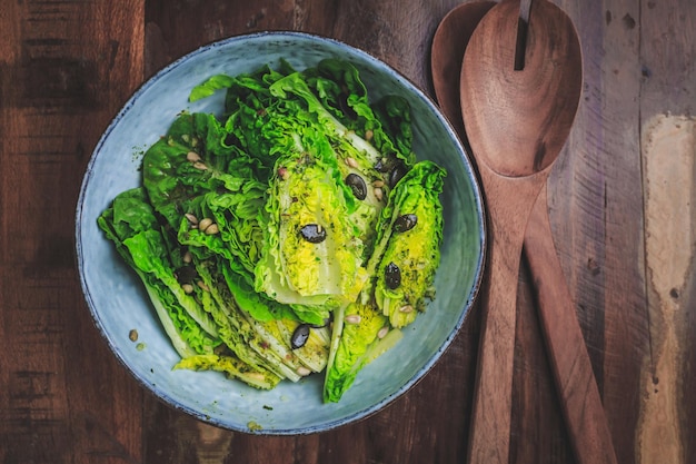 Ciotola di insalata verde mista con semi su fondo di legno