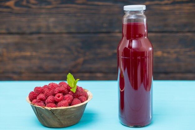 Ciotola di lamponi con succo di frutta in bottiglia