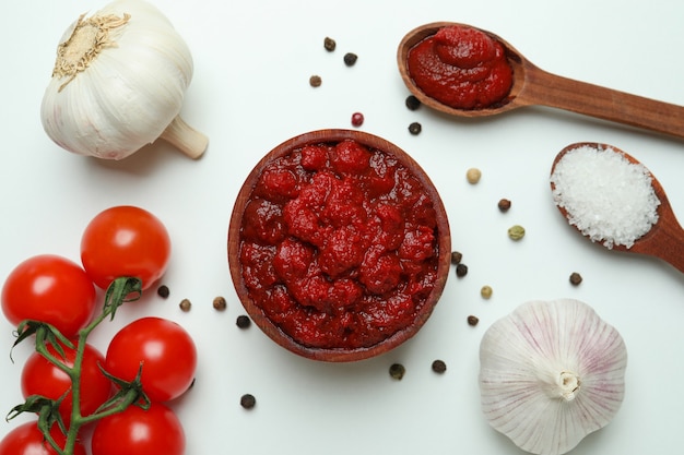 Ciotola di legno con concentrato di pomodoro e ingredienti su bianco