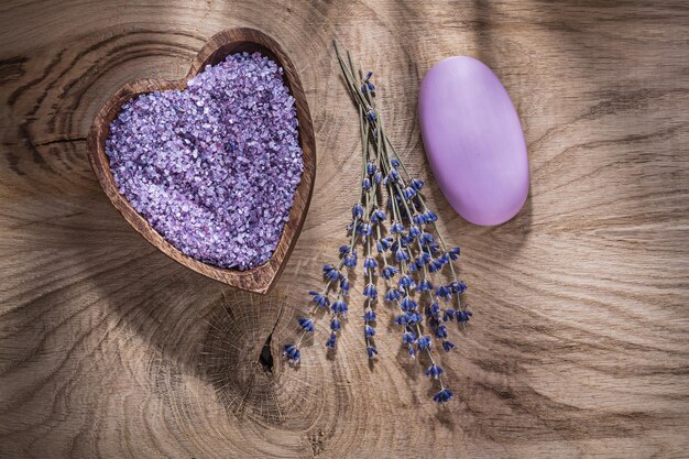 Ciotola di legno con il pezzo di sapone asciutto della lavanda del sale marino sul concetto di trattamento di legno della stazione termale del bordo