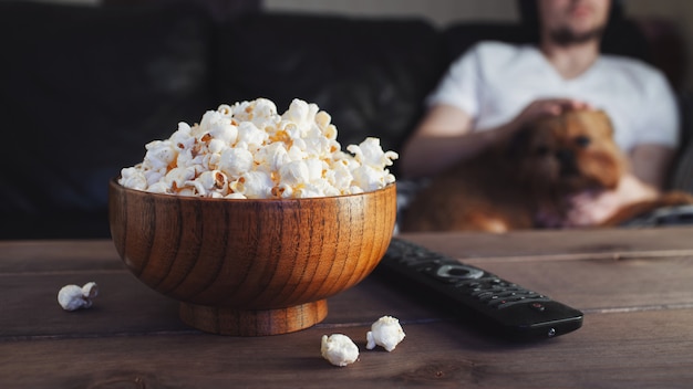 Ciotola di legno con popcorn salato e telecomando TV.