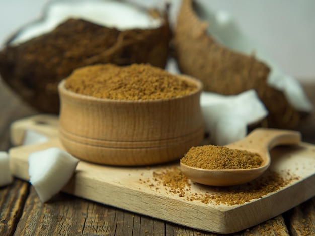 Ciotola di legno e cucchiaio di zucchero di canna con cocco su fondo di legno