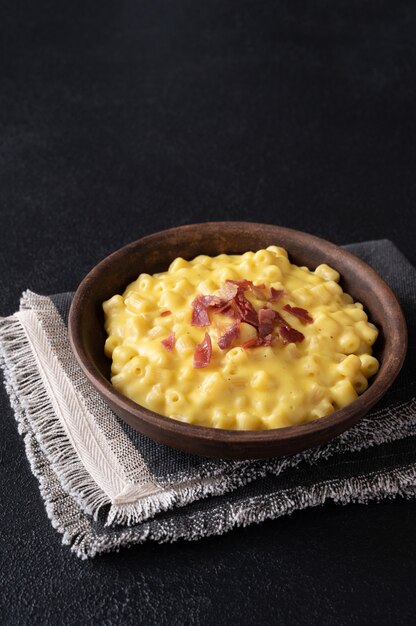 Ciotola di maccheroni e formaggio con fette di pancetta fritta