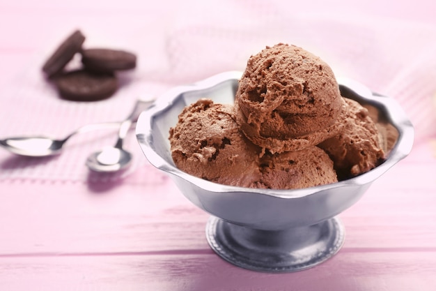 Ciotola di metallo con delizioso gelato al cioccolato rosa sul tavolo di legno