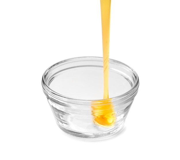 Ciotola di miele versando isolato su sfondo bianco