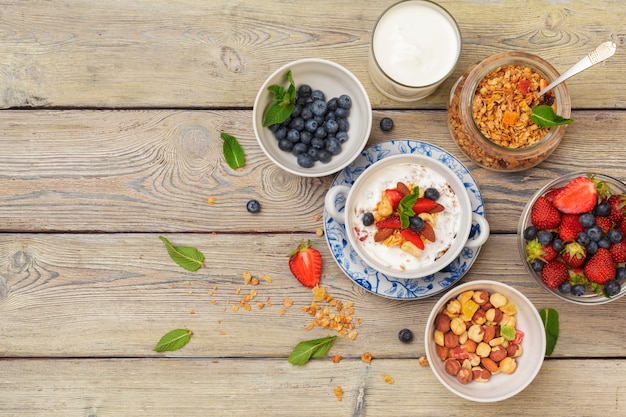 Ciotola di muesli casalingo con yogurt e frutti di bosco freschi su legno