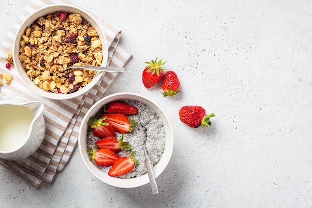 Ciotola di muesli fatta in casa e budino di chia con vista dall'alto di sfondo grigio fragole