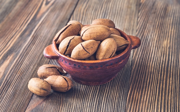 Ciotola di noci pecan sullo sfondo di legno