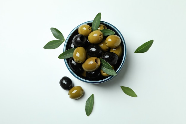 Ciotola di olive e foglie su sfondo bianco isolato, vista dall'alto