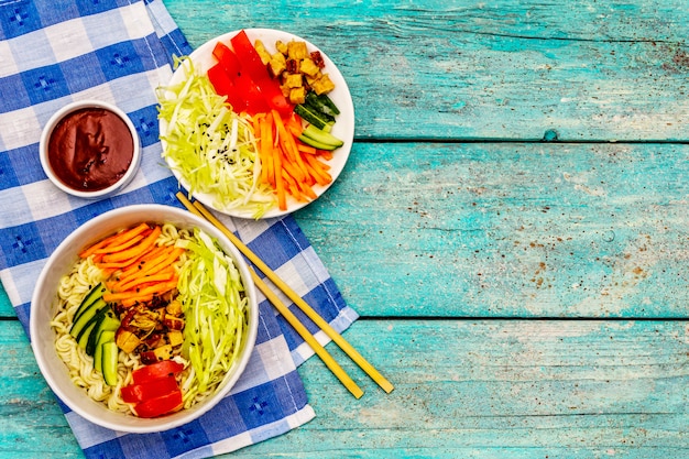 Ciotola di pasta tradizionale coreana con pollo affumicato, verdure affettate fresche e semi di sesamo