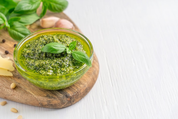 Ciotola di pesto biologico italiano con foglia di basilico verde, aglio, pinoli, formaggio e olio d'oliva