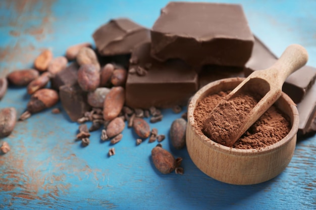 Ciotola di pezzi di cioccolato rotto con polvere di cacao e fagioli su sfondo colorato