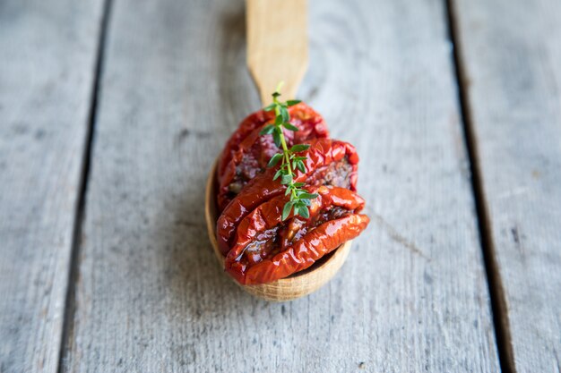 Ciotola di pomodori seccati al sole su fondo di legno. Pomodori essiccati al sole con olio d&#39;oliva ed erbe aromatiche