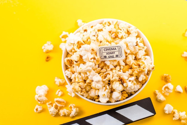 Ciotola di popcorn salati su sfondo giallo. Concetto di spuntino cinematografico. Vista dall'alto piatto