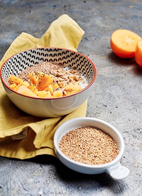 Ciotola di porridge con cachi e chia e noci concetto di cibo sano, vegano